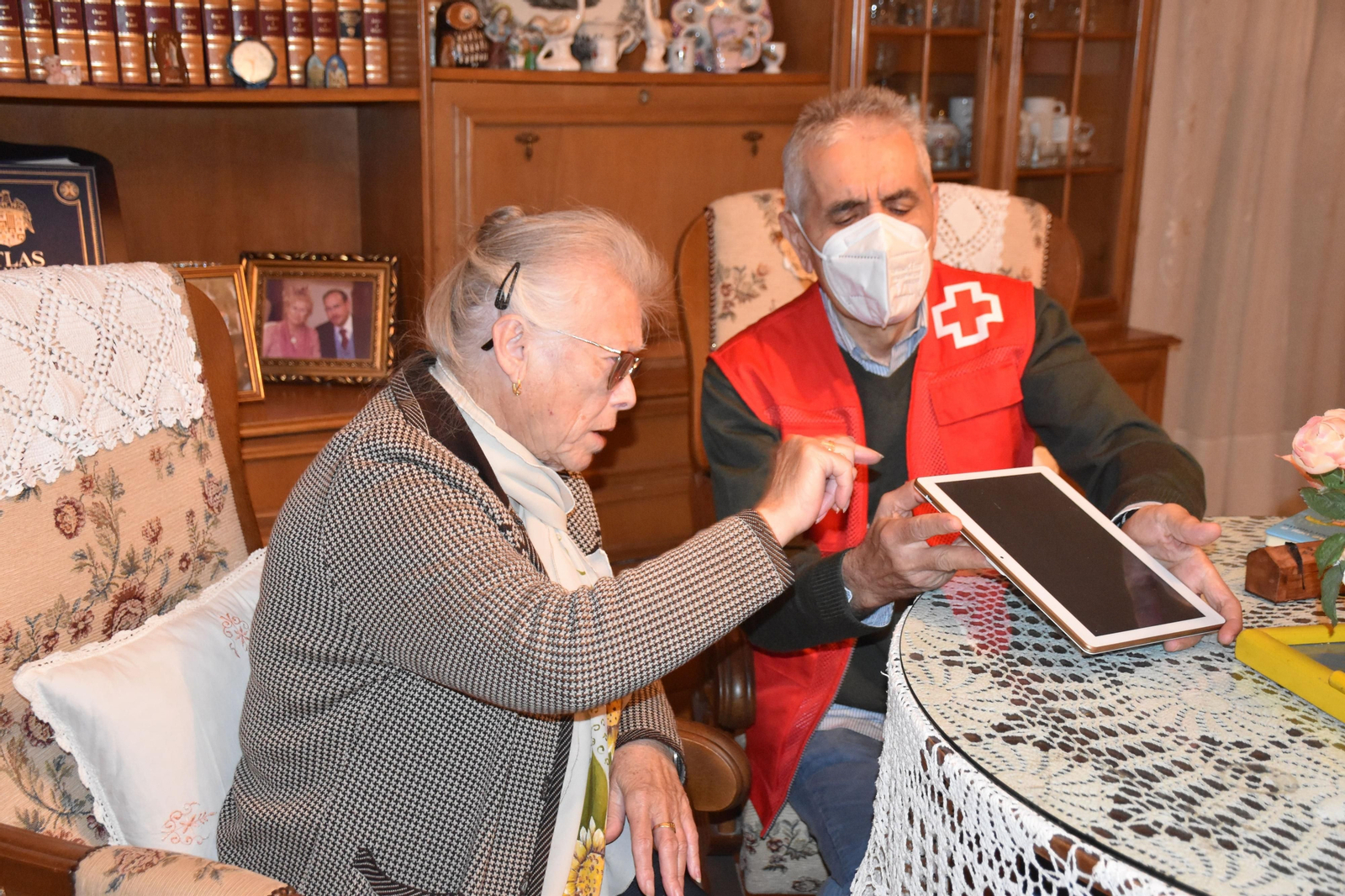 Un voluntario de Cruz Roja ayuda a una mujer a manejarse con una tablet. Un voluntario de Cruz Roja ayuda a una mujer a manejarse con una tablet.