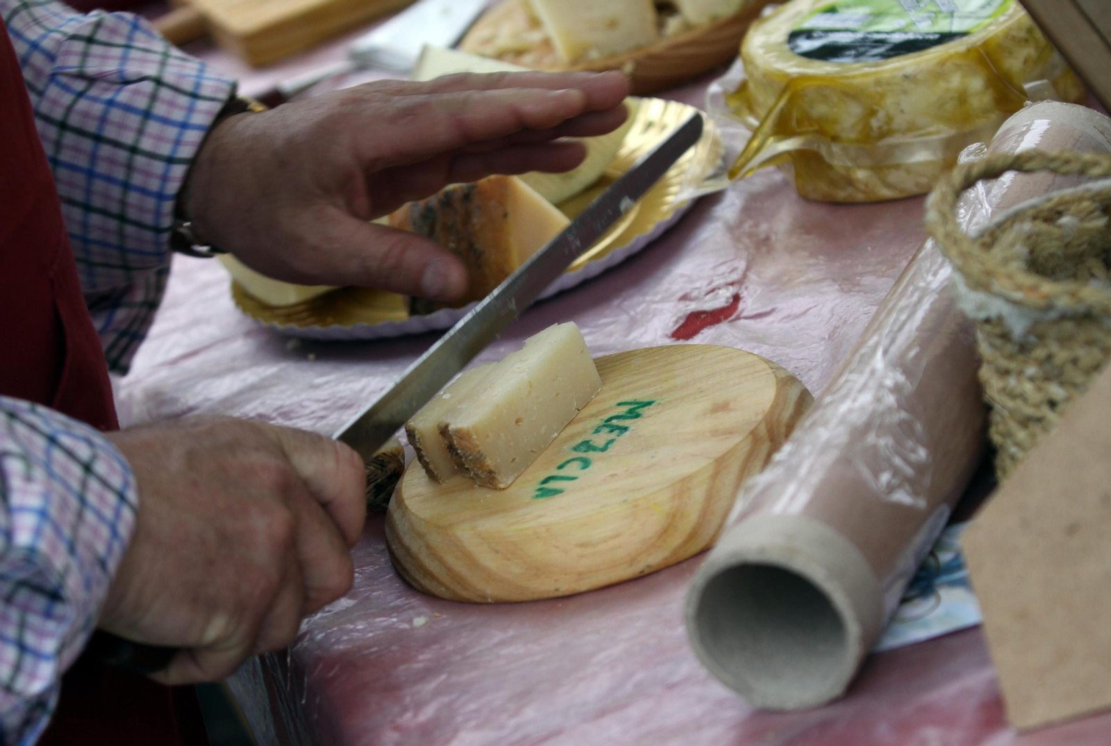 Un hombre corta queso durante el mercado de quesos. Un hombre corta queso durante el mercado de quesos.