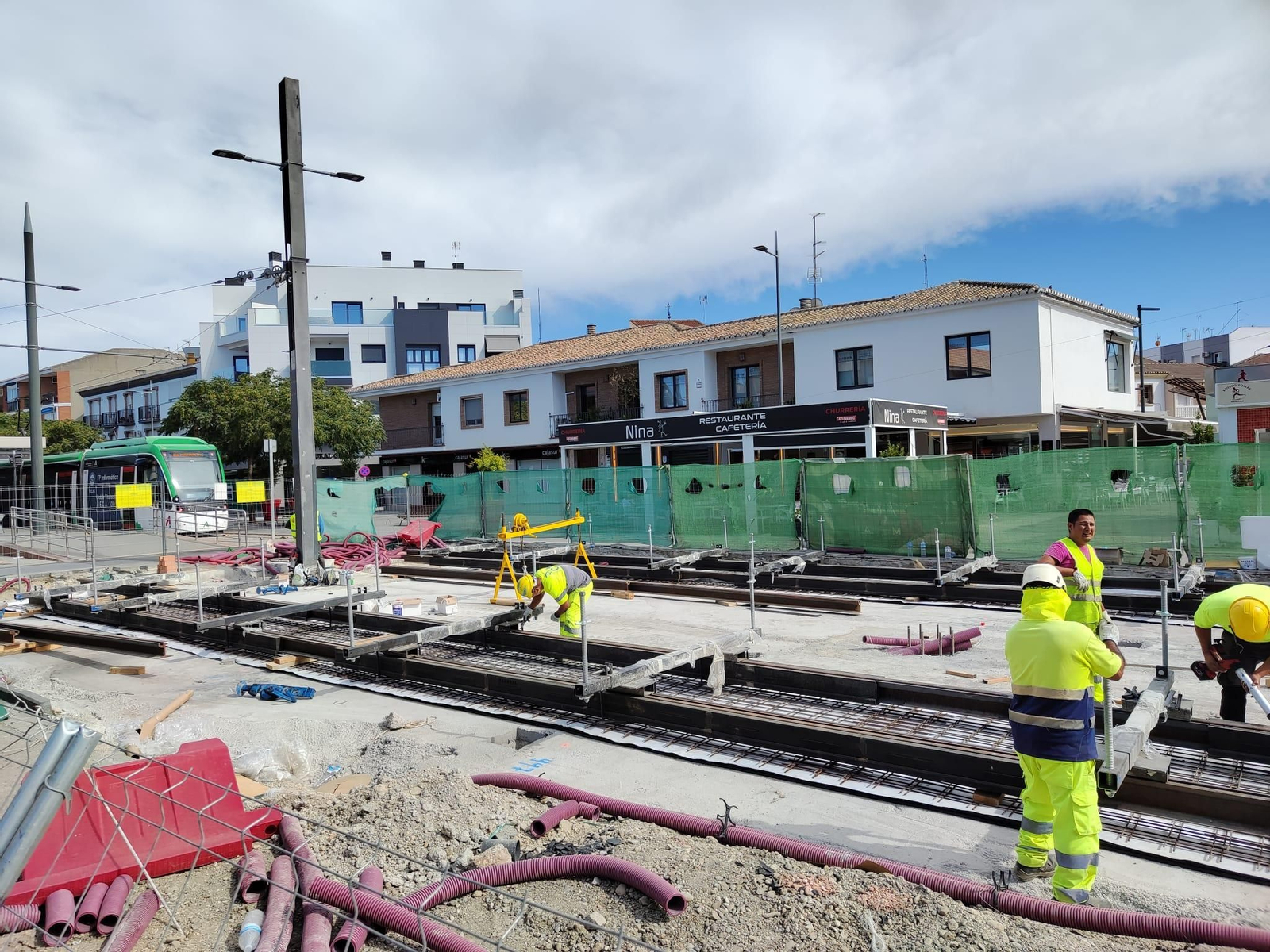 Trabajadores colocando vías en la Plaza de la Constitución de Armilla, a continuación de la última parada