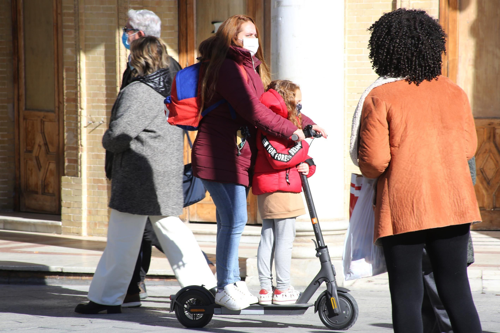 Una mujer y una niña, en un patinete eléctrico por el centro de Jerez.