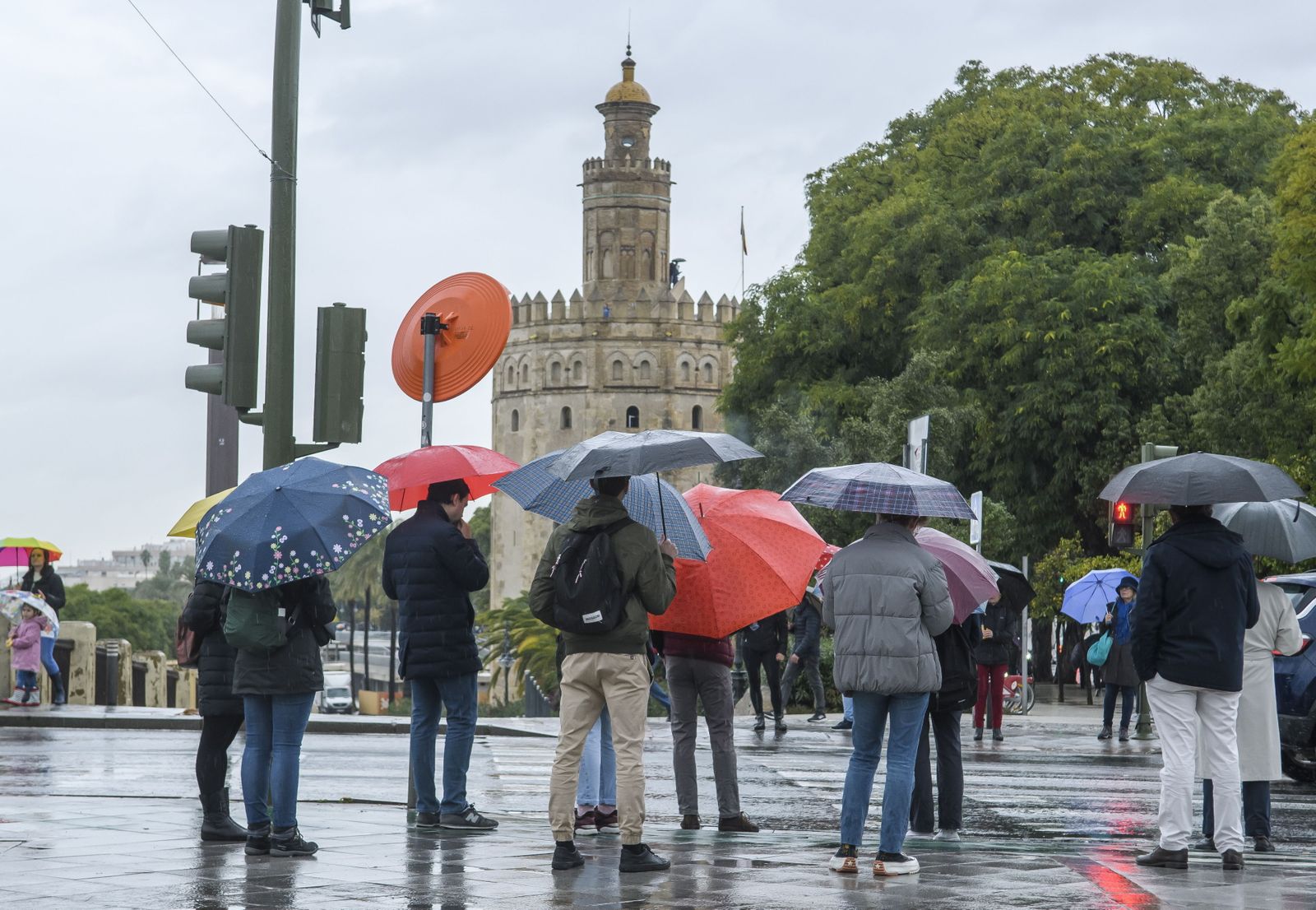 Varias personas se refugian debajo de sus paraguas, en Sevilla.