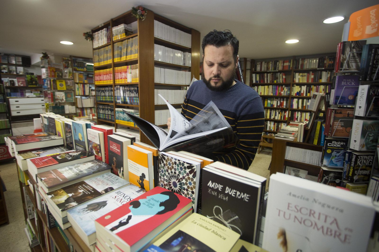 Un dependiente hojea un libro en Saltés (calle Ciudad de Aracena), librería de referencia en la capital onubense desde hace cuatro décadas.