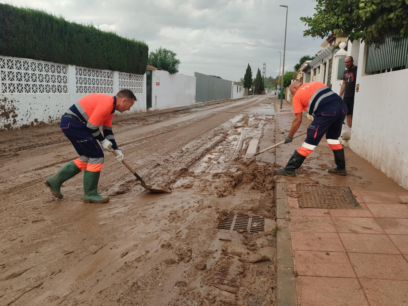 Operarios de Limasam quitan barro de la calle Degas, en Campanillas, delante de la casa de Álvaro Aquilar.