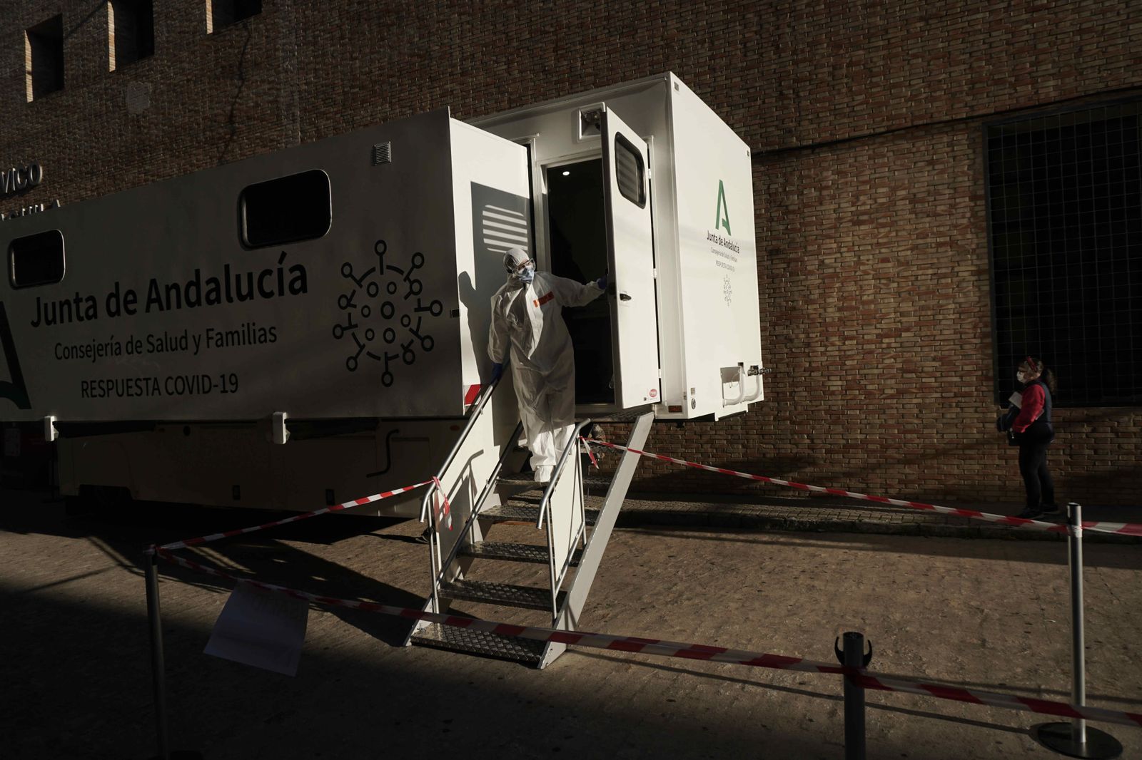 Un profesional sanitario se asoma desde el interior de la unidad móvil instalada junto al Centro Cívico Cerro del Águila.