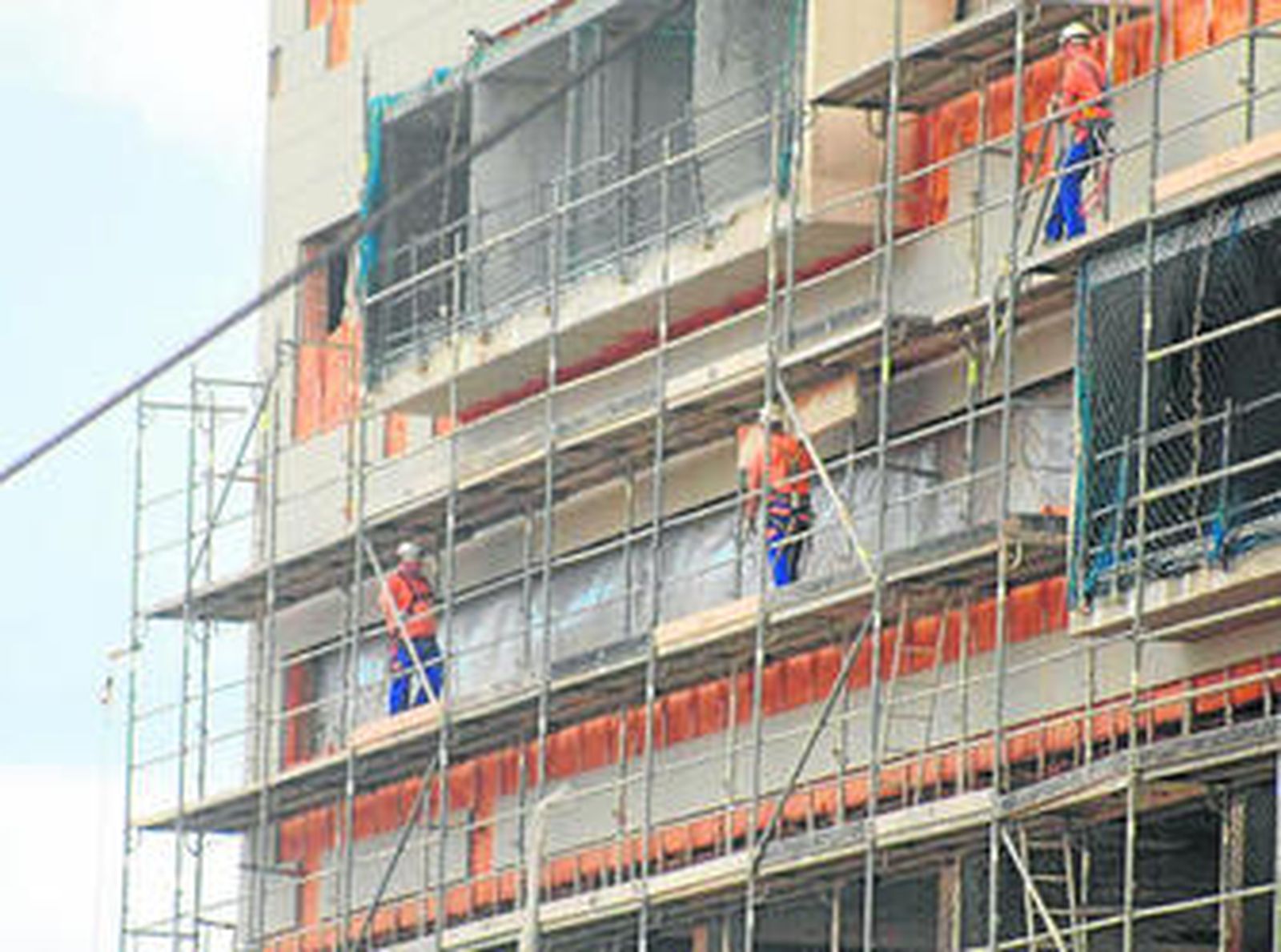 Operarios trabajan ayer en desmontar los andamios del edifico por construir en el que iría un nuevo hospital.