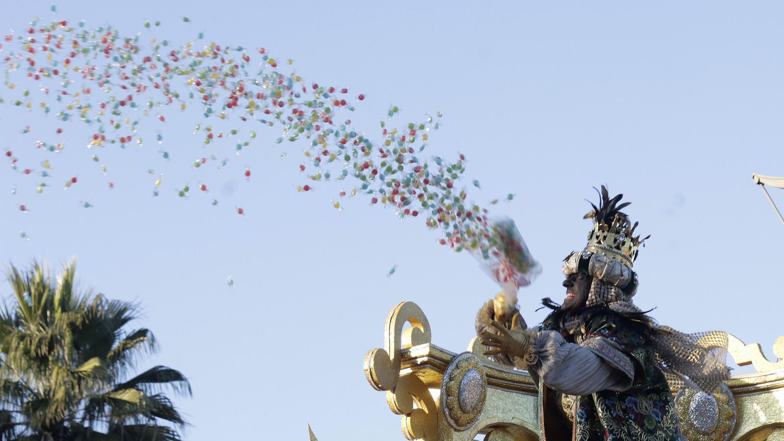 El rey Baltasar tira impulsa al cielo un puñado de caramelos.