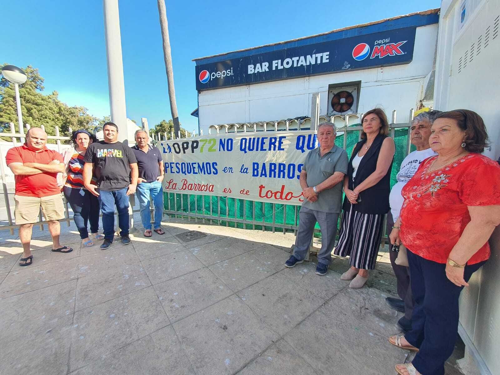 Los pescadores de Sancti Petri despliegan una pancarta junto a la concejala de Fomento.