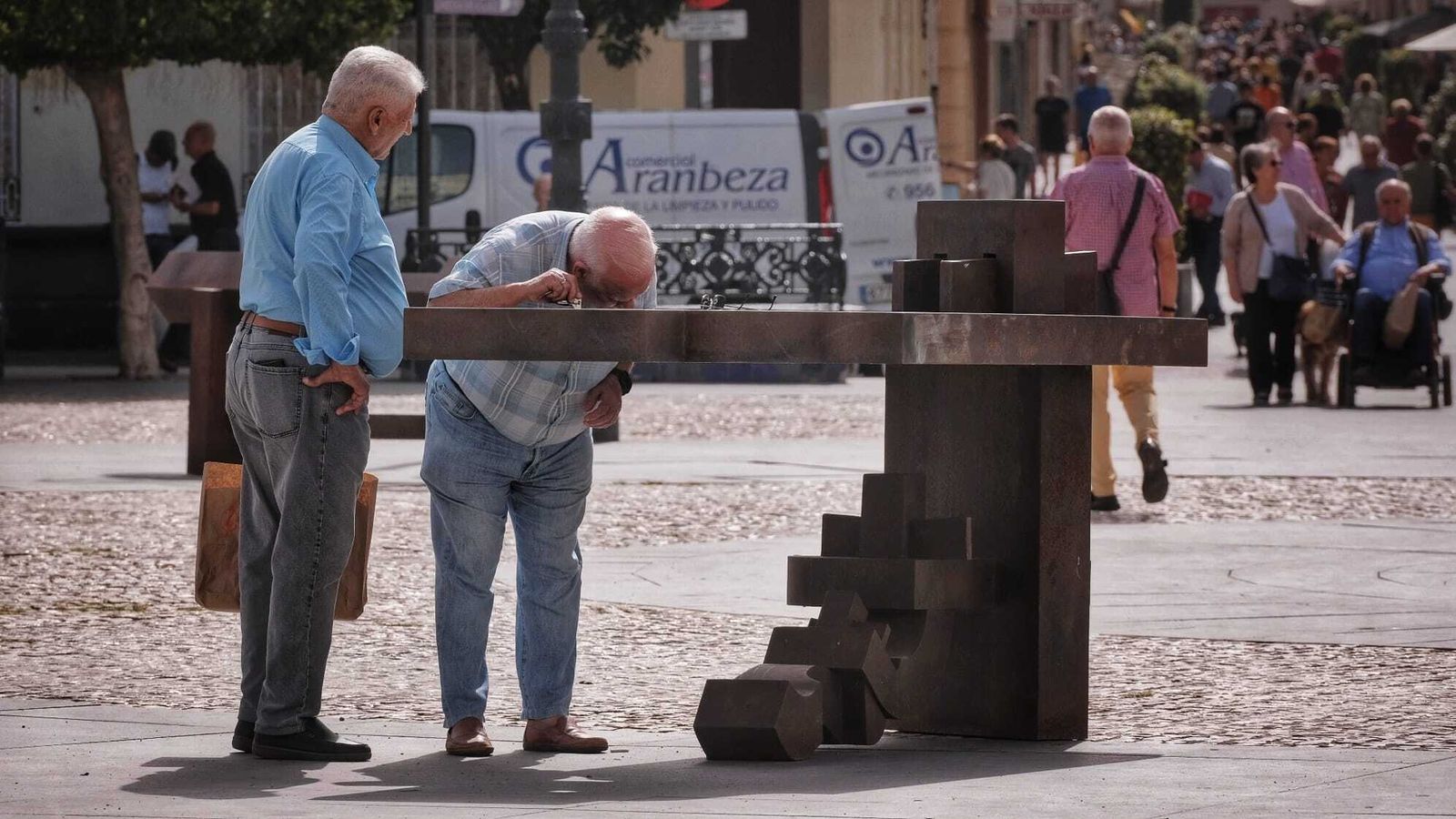 Dos ciudadanos junto a una de las obras de la exposición 'El canto del hierro' de Kieff Antonio Grediaga.