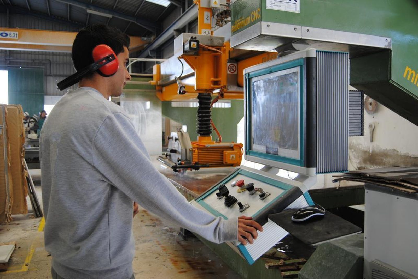 Un alumno aprendiendo a manejar la maquinaria de la Escuela de Mármol.