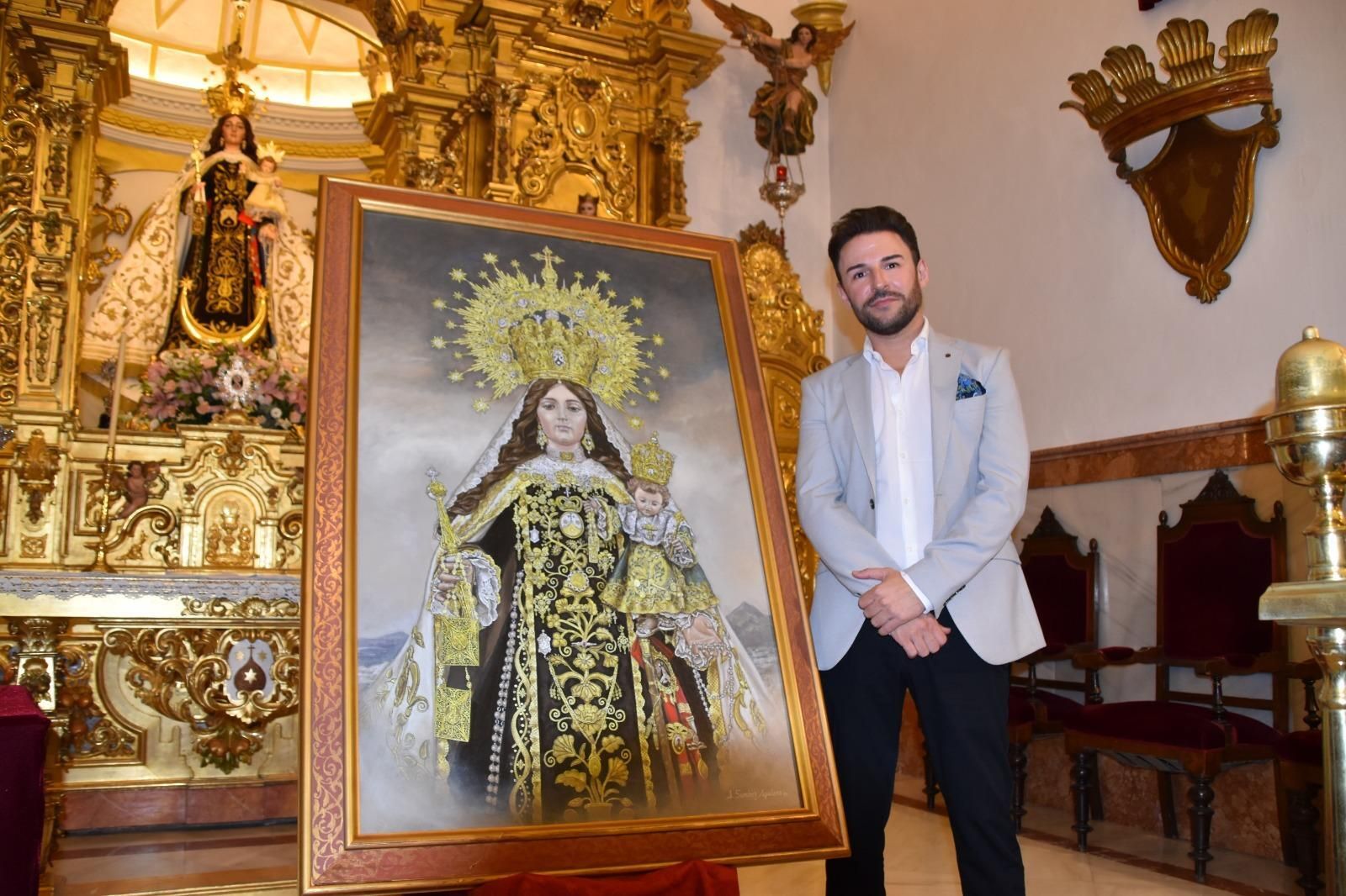 El pintor Jonathan Sánchez, junto al cartel del centenario del patronazgo de la Virgen del Carmen en Rute.