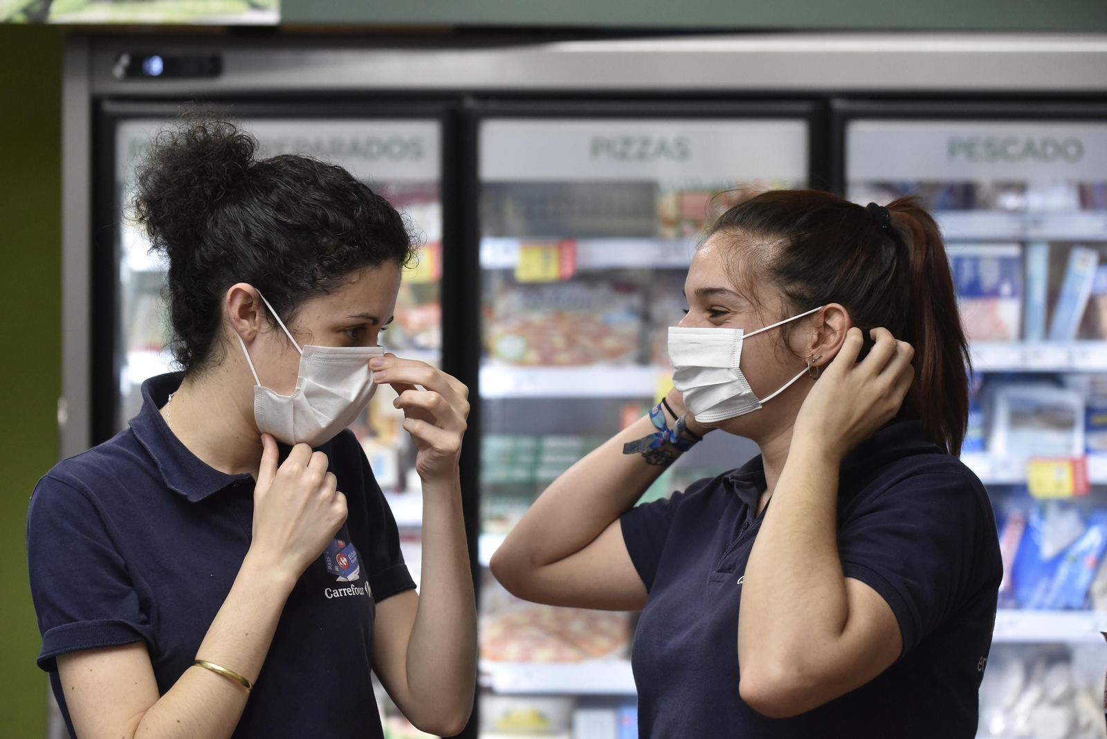 Dos cajeras de un supermercado se colocan sus mascarillas.