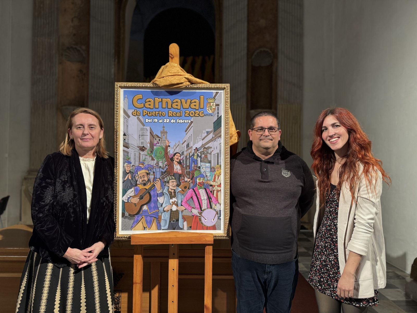 La alcaldesa y la edil de Fiestas junto al autor del cartel del Carnaval de Puerto Real 2026