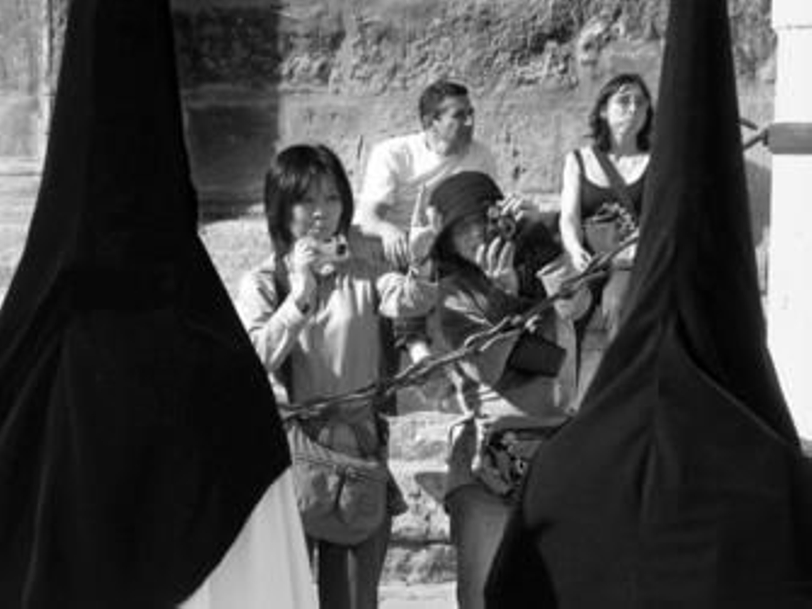 Un grupo de turistas toma fotografías del paso de una cofradía junto a la Catedral.