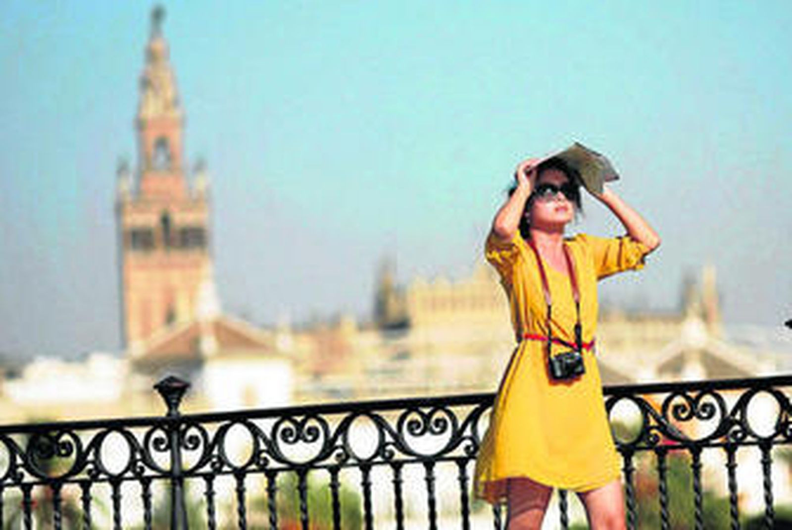 Una turista que pasea por el puente de Triana se protege del sol.