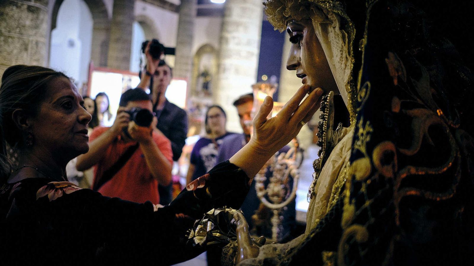 Una mujer toca con sus manos el rostro de la Virgen del Rosario del Perdón