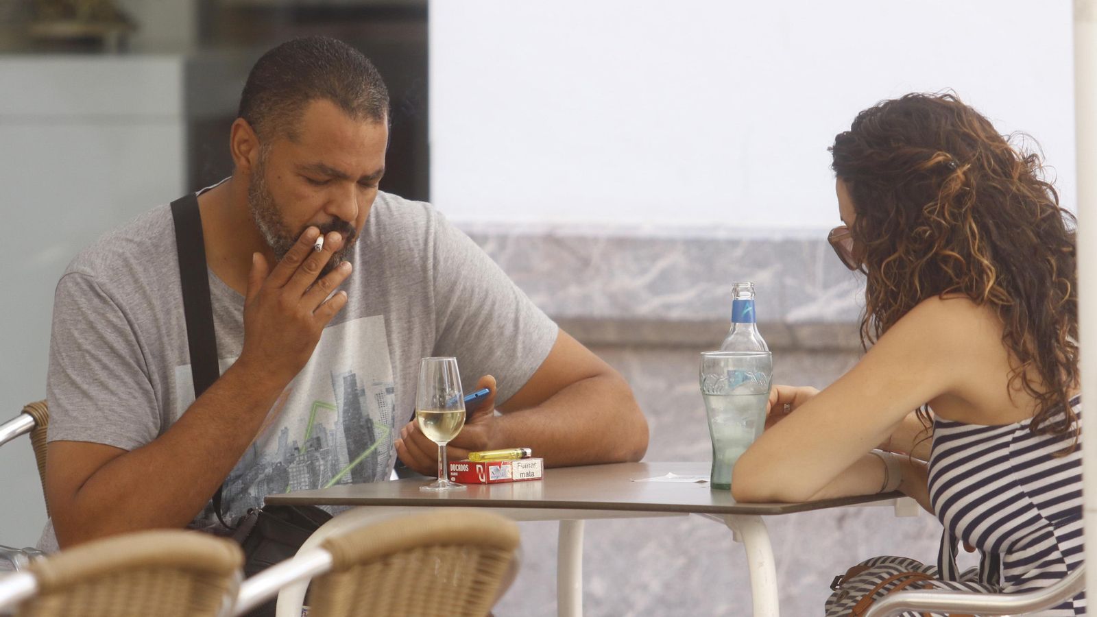 Una pareja fuma un cigarrillo en una terraza