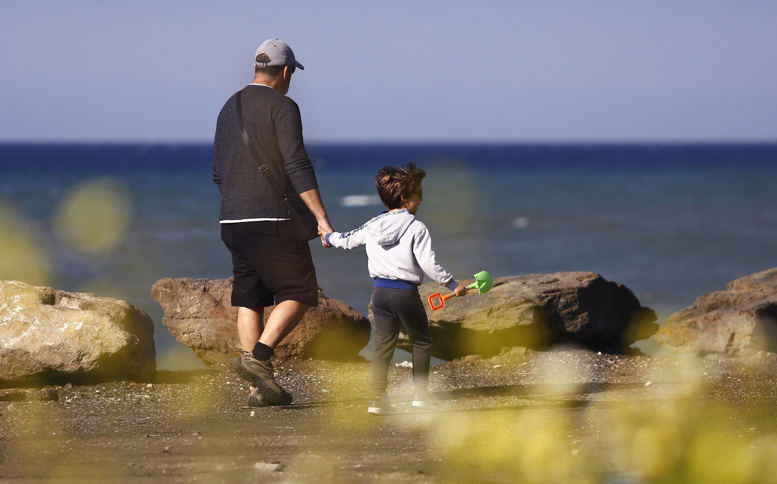Un niño pasea, acompañado por un adulto, en una playa de Málaga capital.