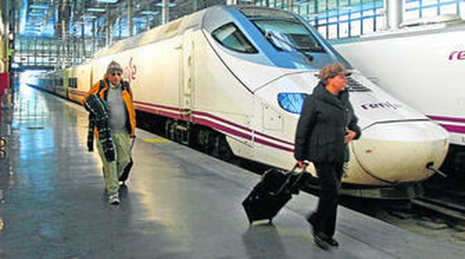 Dos viajeros descienden de un tren Alvia que realiza el recorrido entre Madrid y Cádiz en tres horas y 58 minutos.