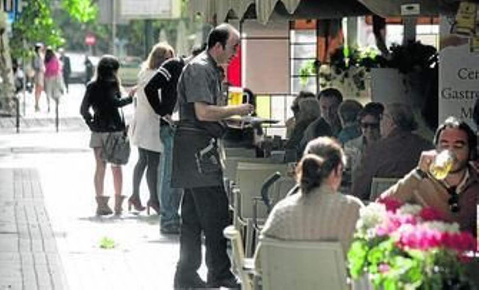Un camarero atiende las mesas de un bar.