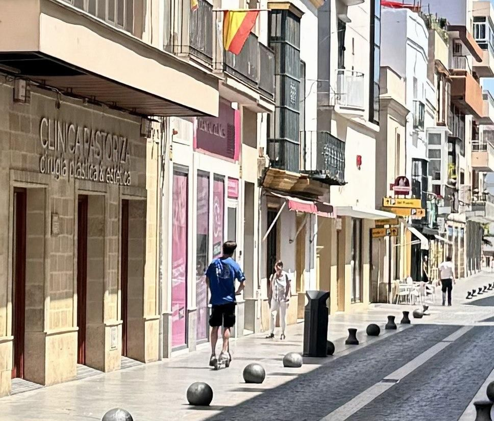 Un joven circulando en patinete por una acera de la ciudad.