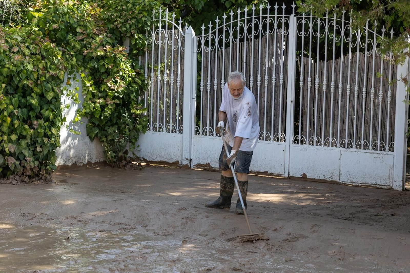 Un vecino limpia el barro que anega las calles.