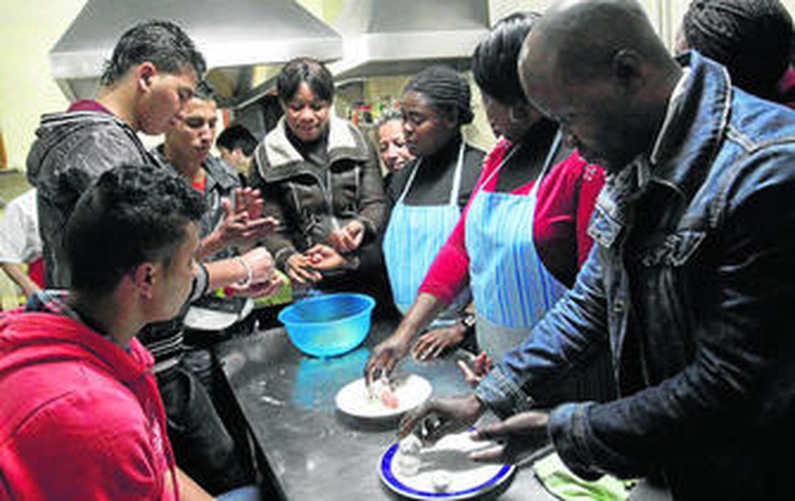 Los inmigrantes participantes en el curso de cocina haciendo albóndigas.