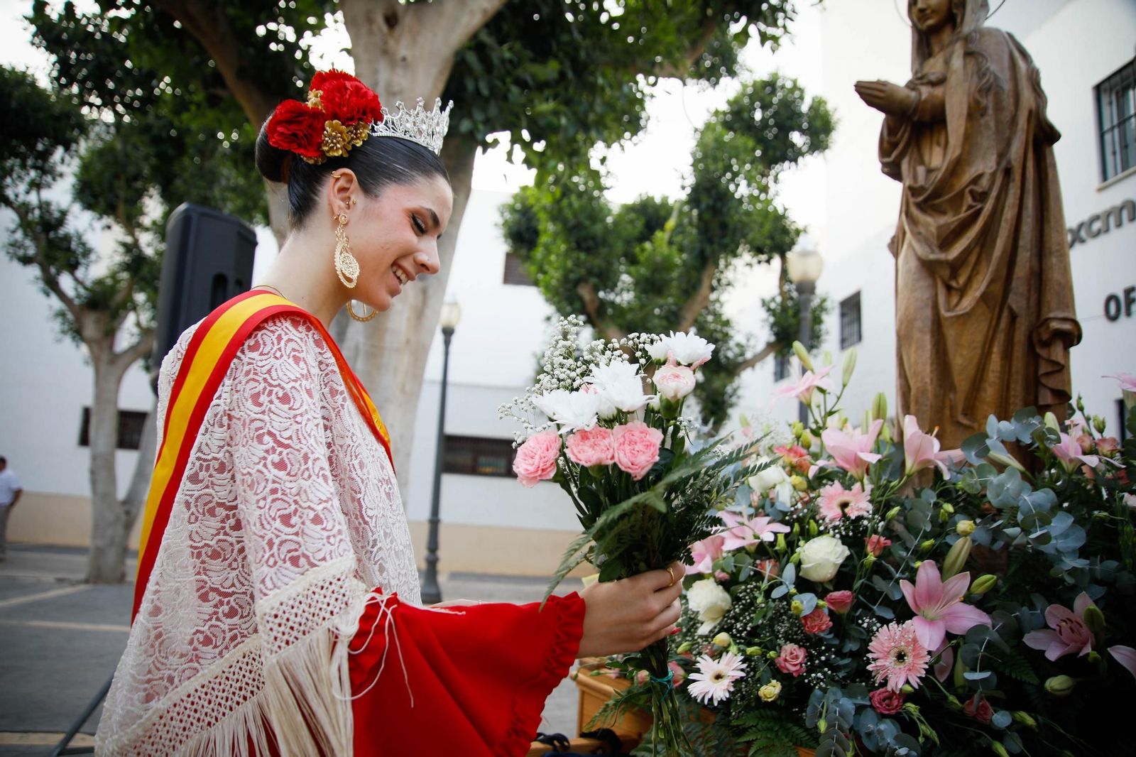 Momento en el que una veina coloca una ofrenda floral a los pies de la Virgen Momento en el que una veina coloca una ofrenda floral a los pies de la Virgen