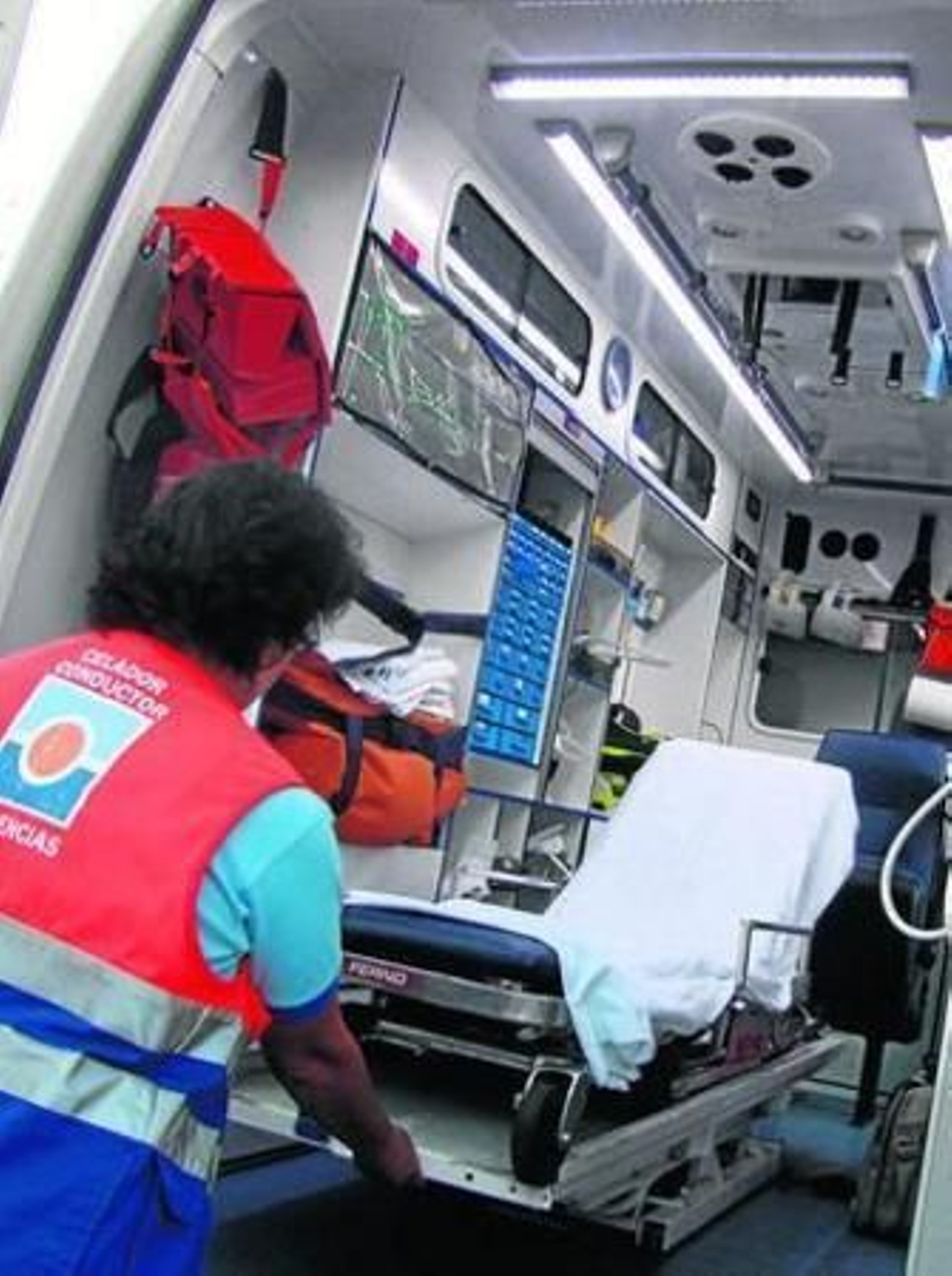 Un conductor de ambulancia se dispone a sacar la camilla.
