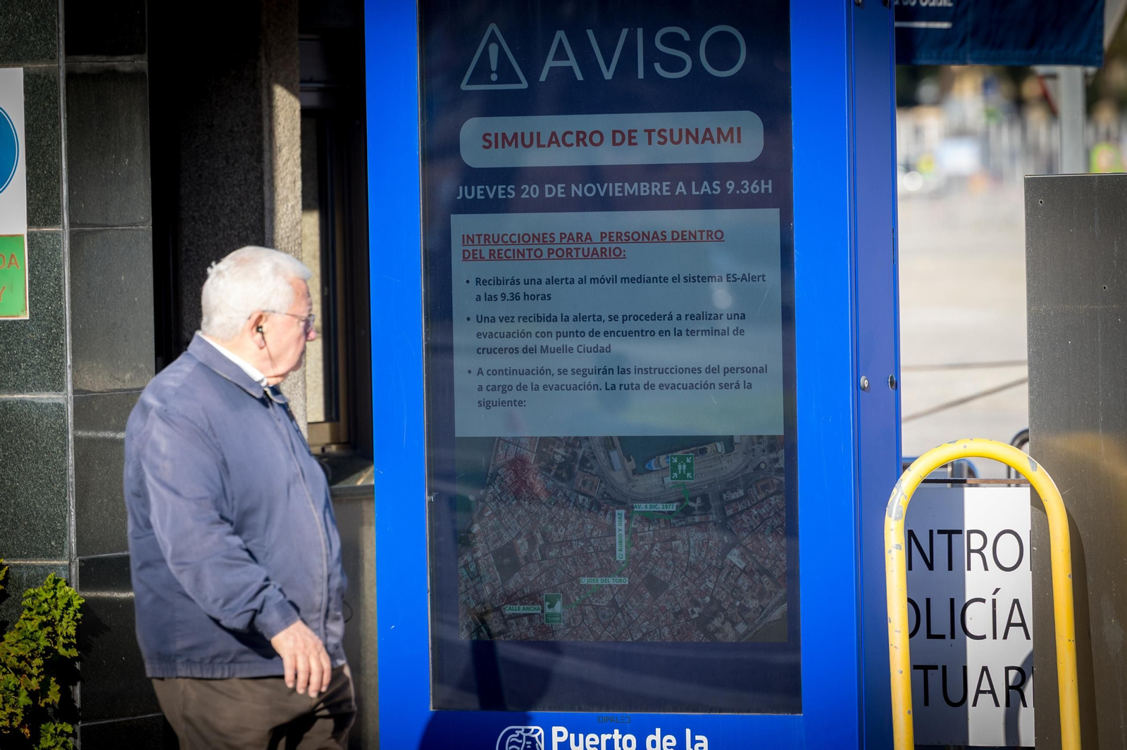 Un hombre pasa por delante del mensaje de alerta de simulacro en el Puerto de Cádiz.