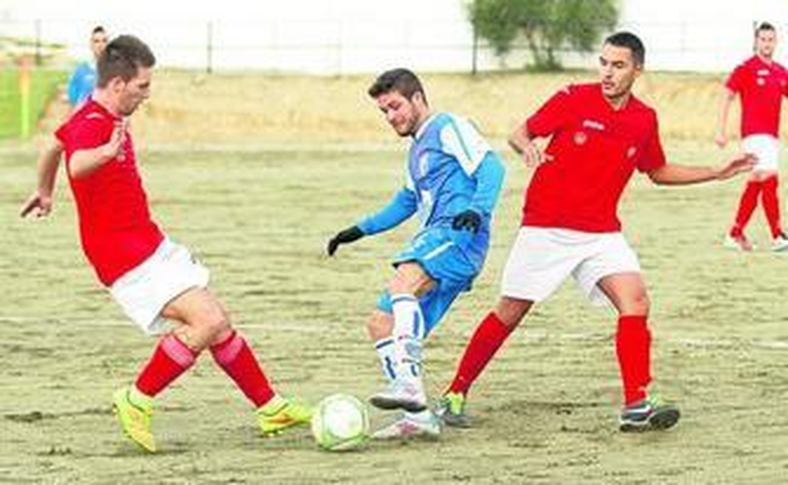 Un jugador del Monachil trata de llevarse la pelota entre dos futbolistas del Águilas de Zujaira.