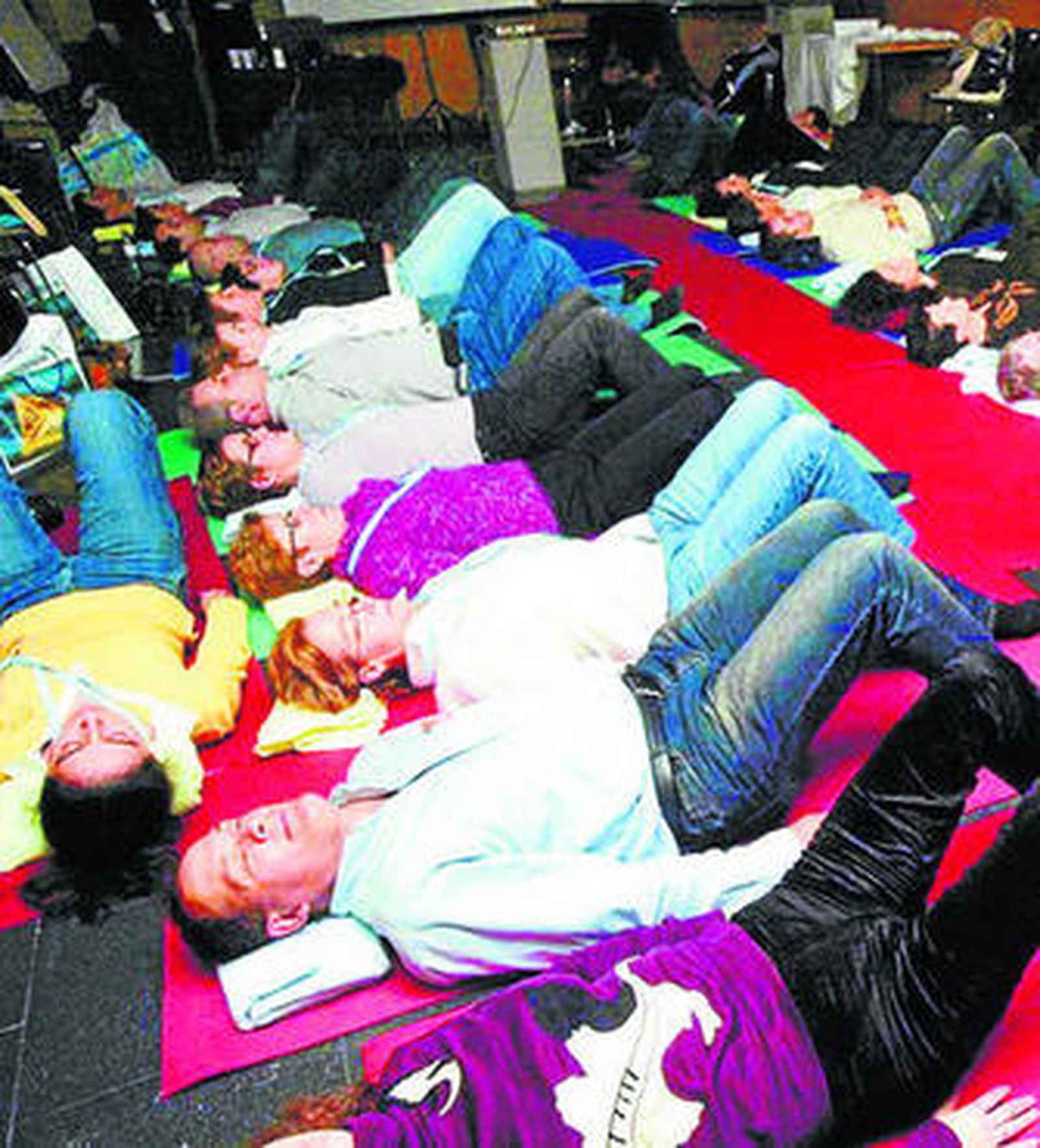 Un grupo de personas realiza ejercicios de relajamiento de la columna vertebral.