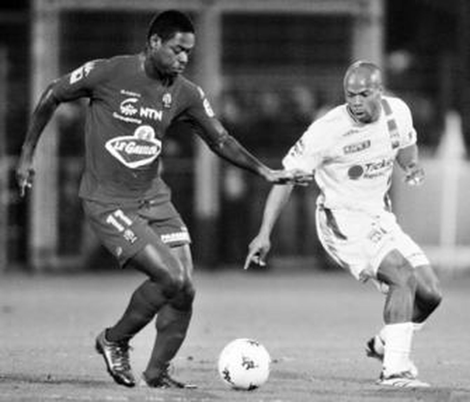 Romaric avanza con el balón controlado ante Wiltord en un partido entre el Le Mans y el Lyon.