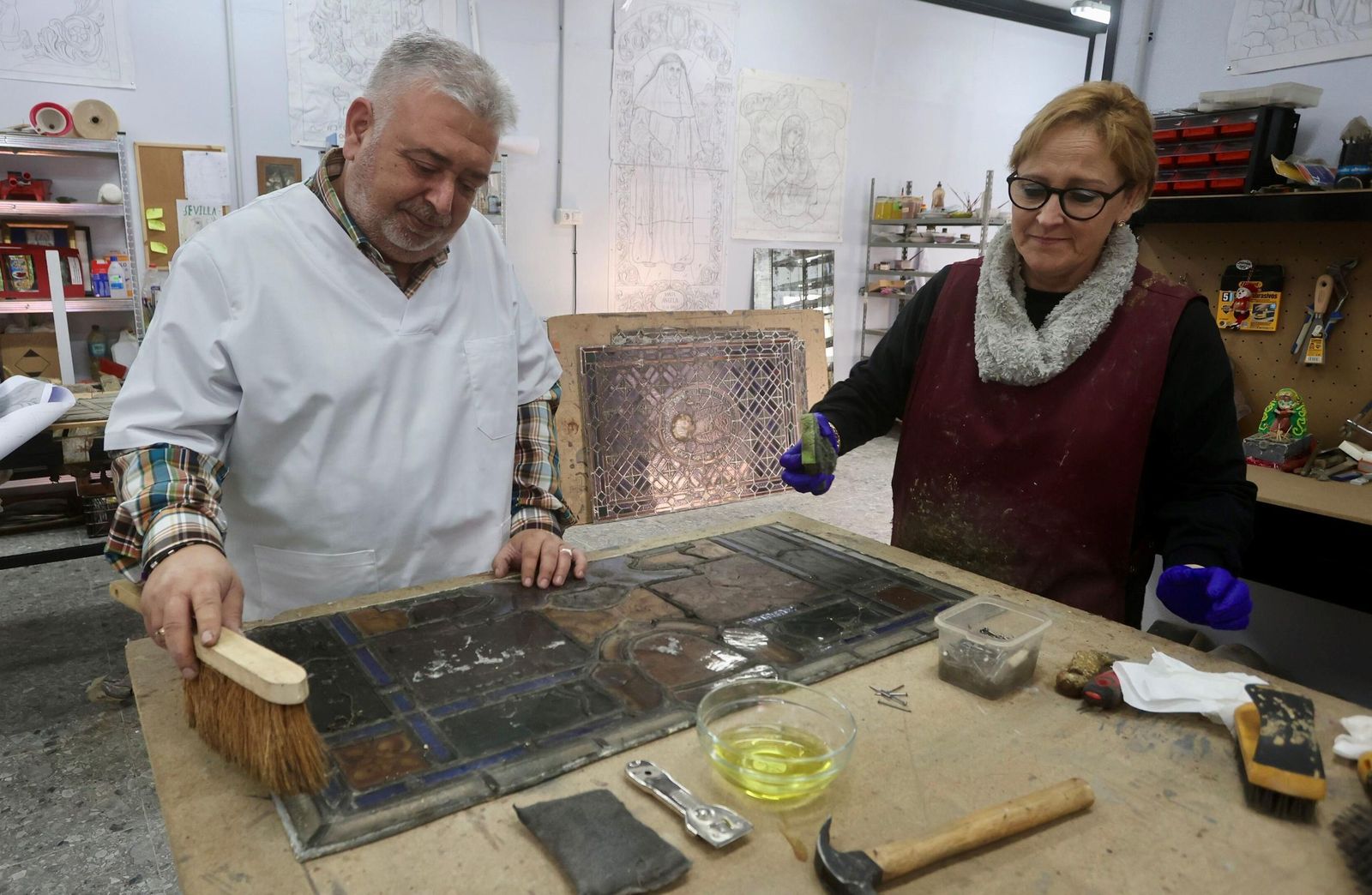 Antonio Javier Salgado y María del Rosario Hernández limpian una vidriera que hay que restaurar.
