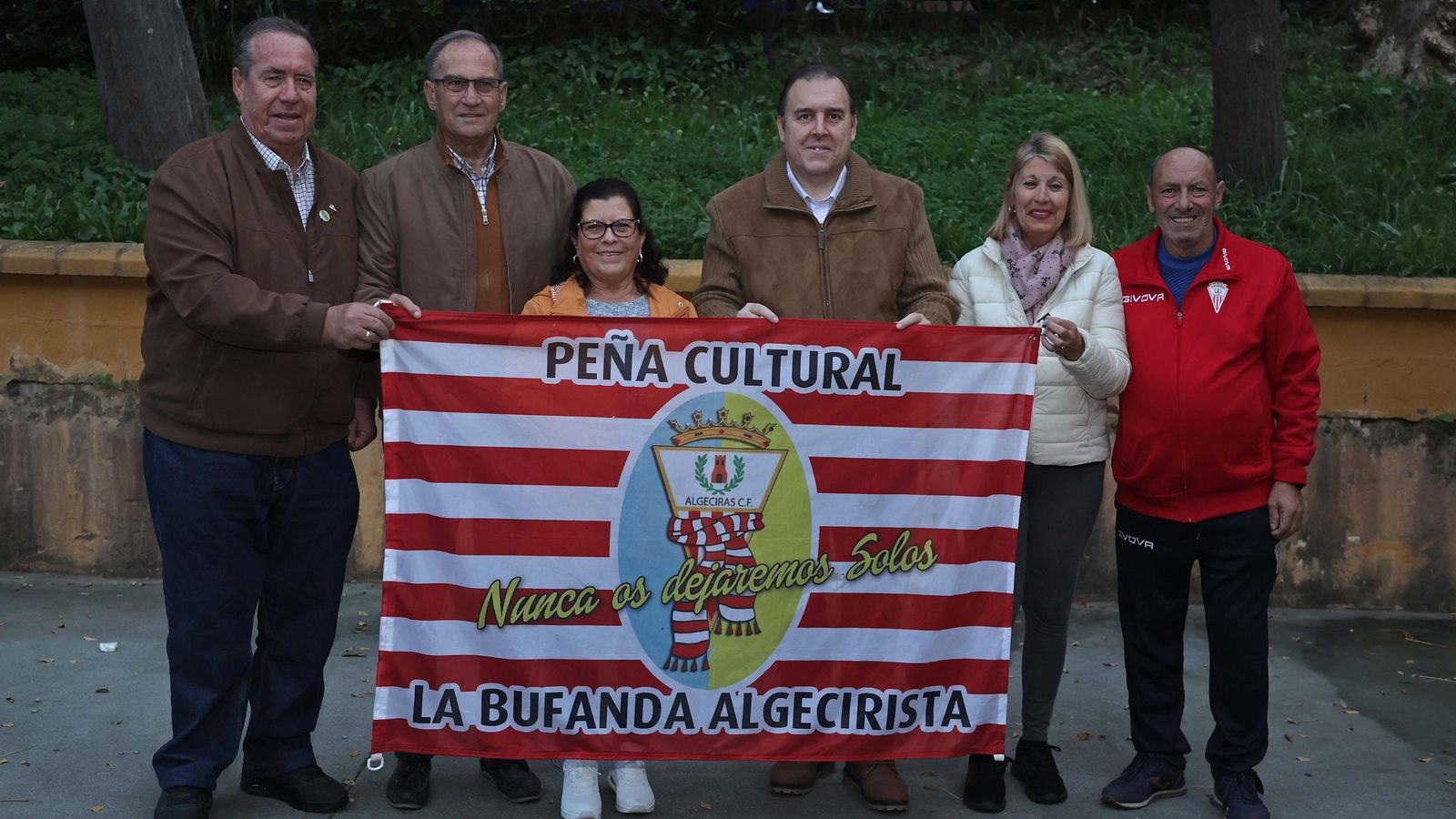 El grupo luce bandera de la peña cerca de la puerta de la asociación vecinal