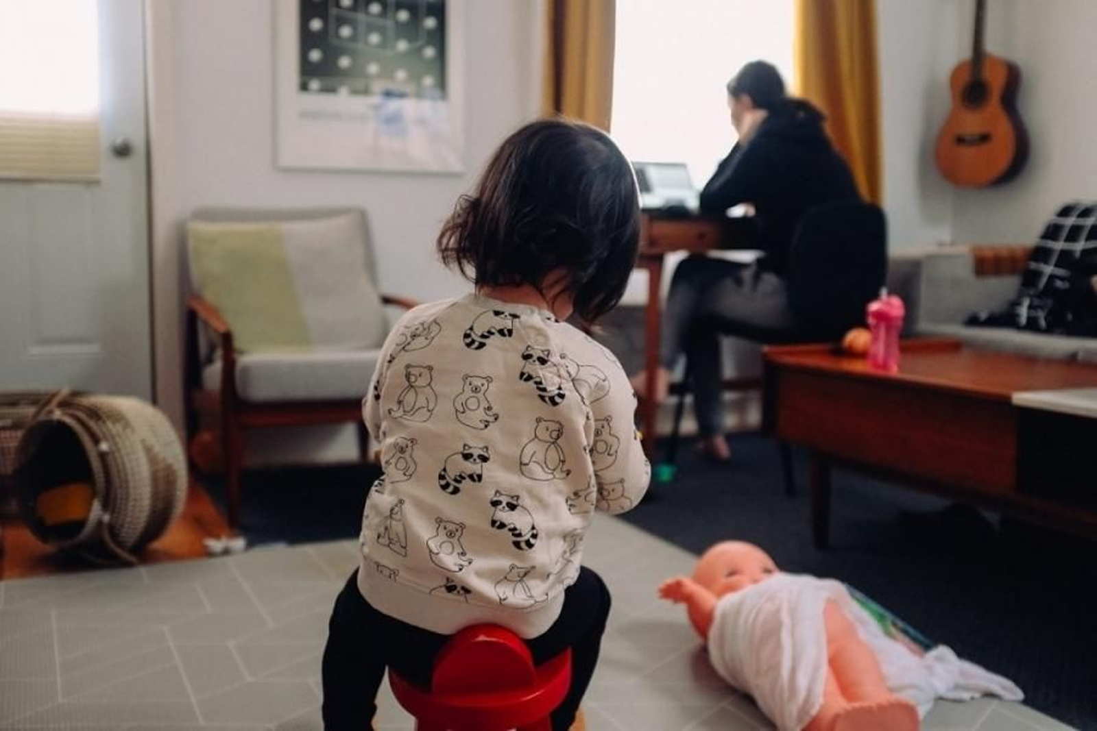 Una niña juega mientras su madre trabaja.