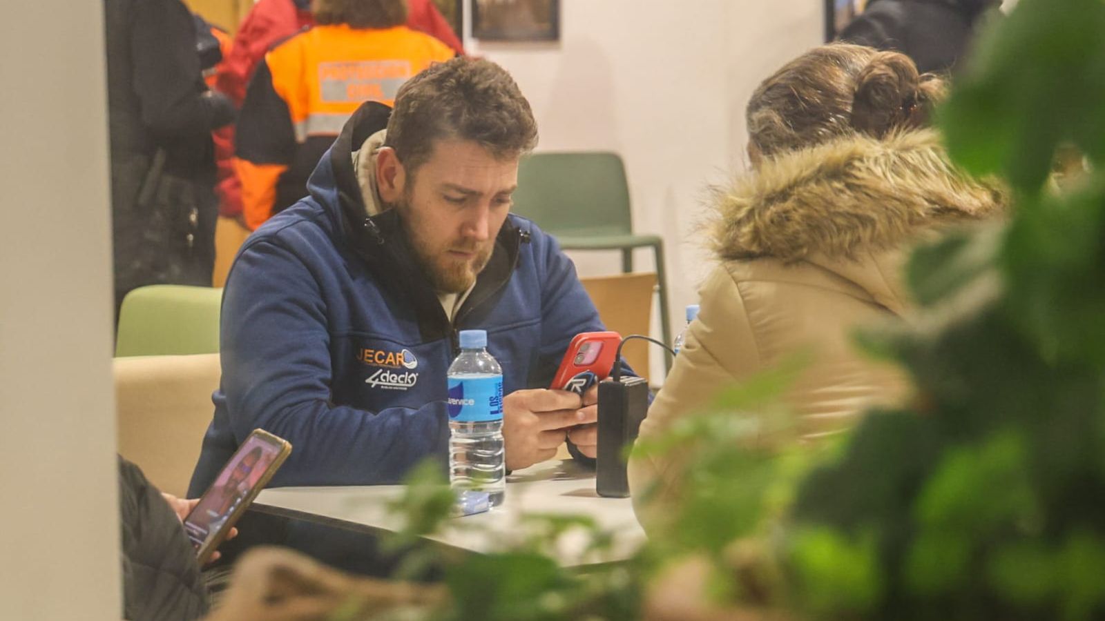 Un joven consulta su teléfono móvil mientras espera noticias.