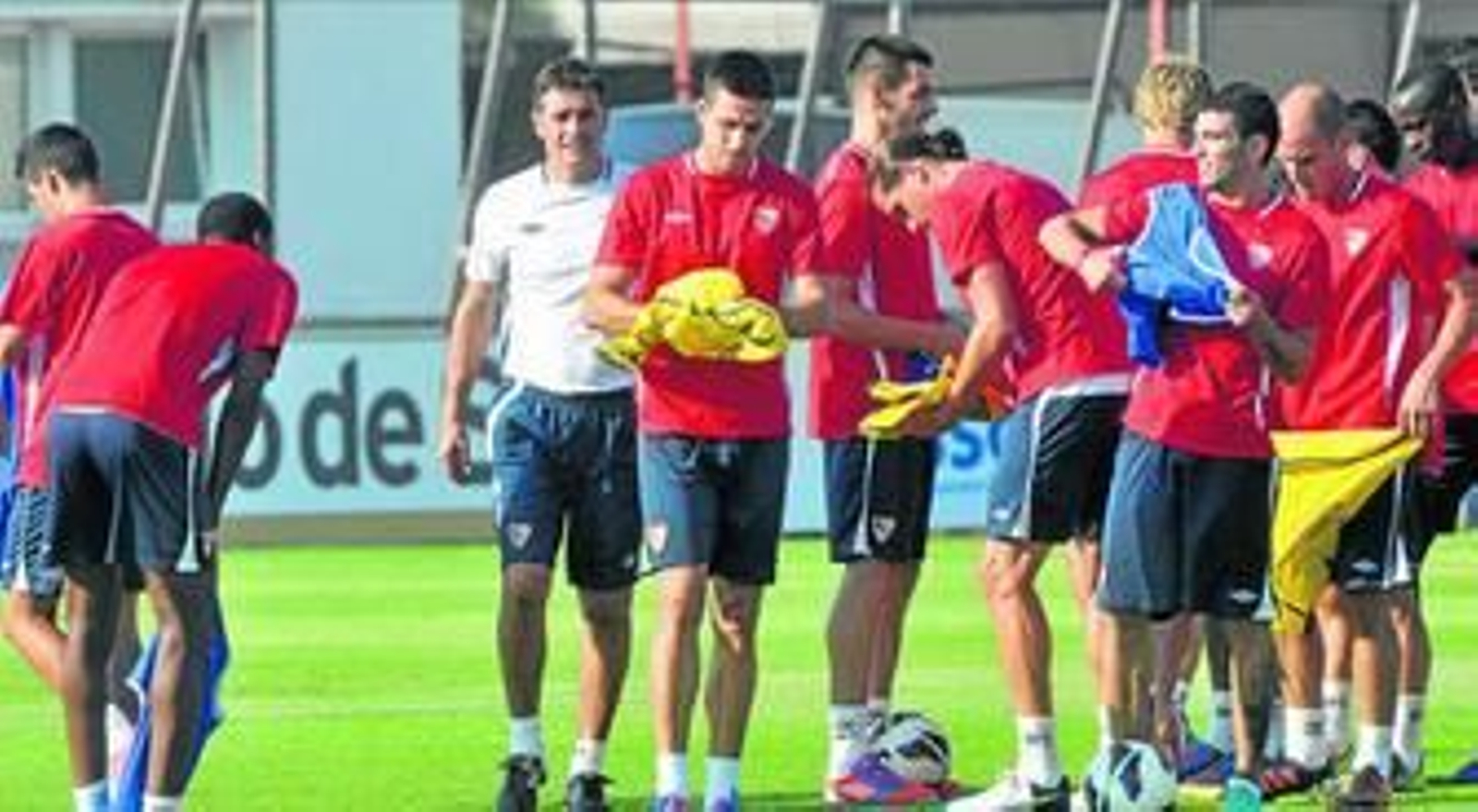 Míchel, rodeado de un nutrido grupo de jugadores que se reparten los petos para un ejercicio.