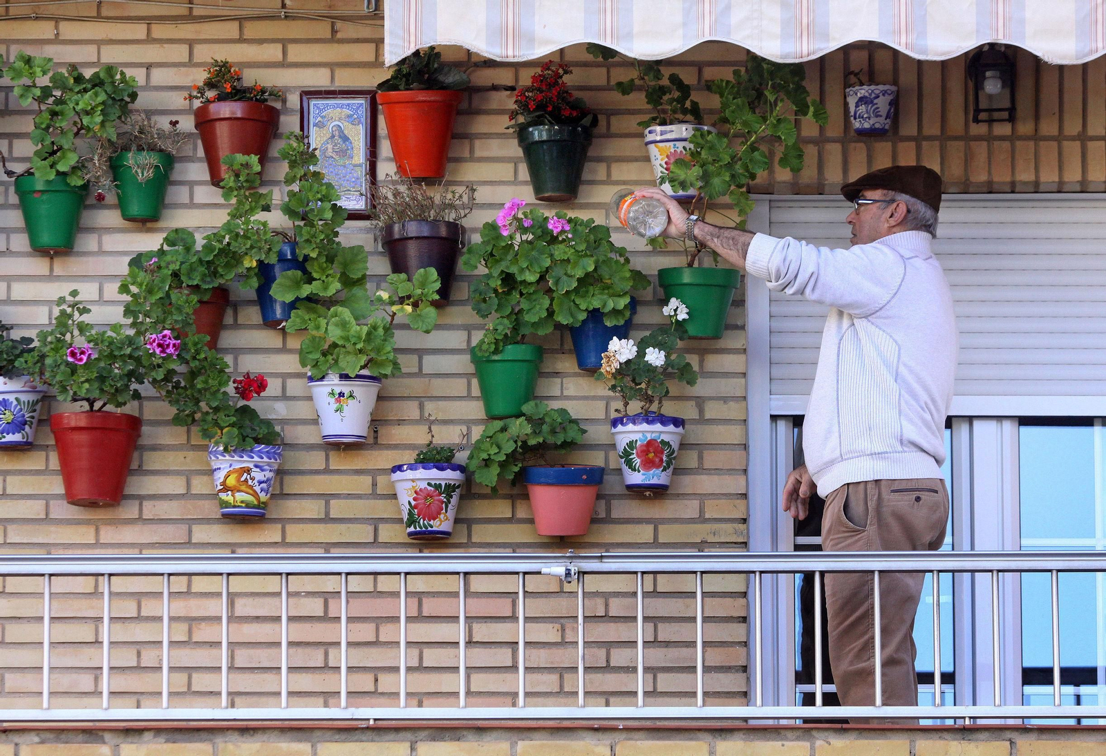 Un hombre riega las macetas en un balcón. Un hombre riega las macetas en un balcón.