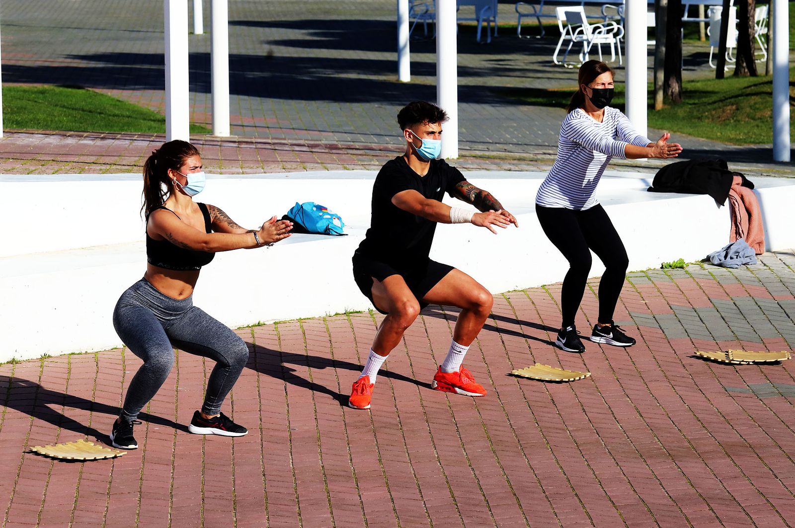 Tres personas realizan ejercicio en la calle