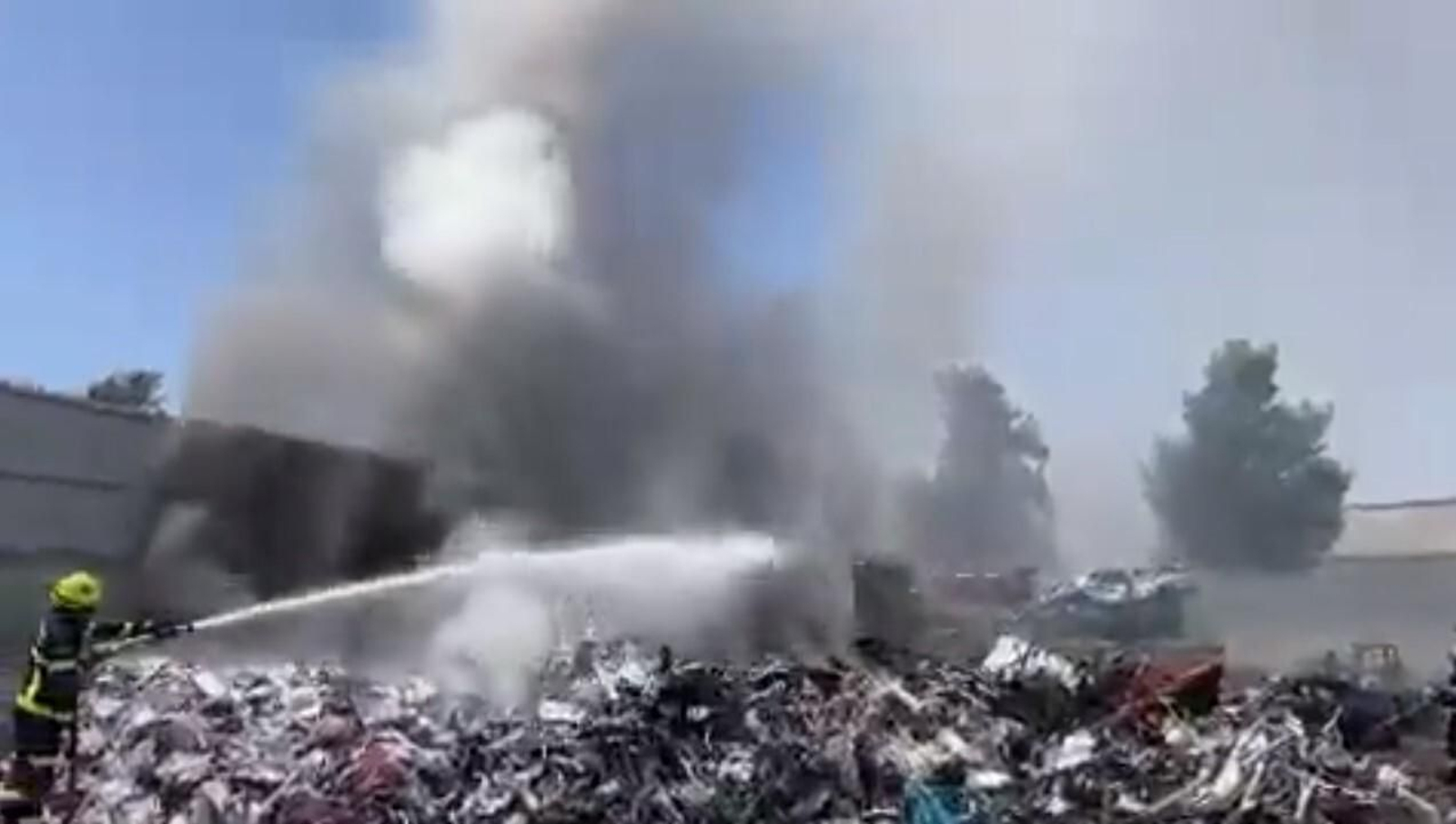 Un bombero interviniendo en la extinción de un fuego en una chatarrería (captura de vídeo).