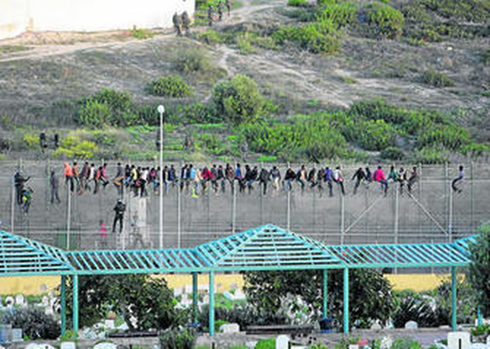 Un grupo de inmigrantes subsaharianos encaramados sobre la valla fronteriza de Melilla el pasado miércoles.