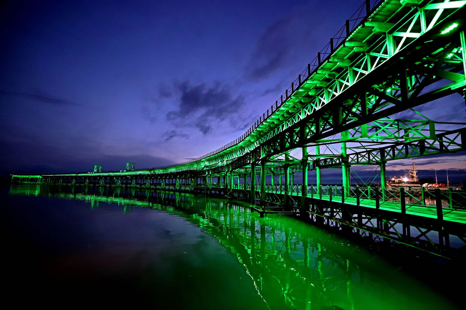 El muelle de la Riotinto se ilumina de verde en el día mundial contra el cancer