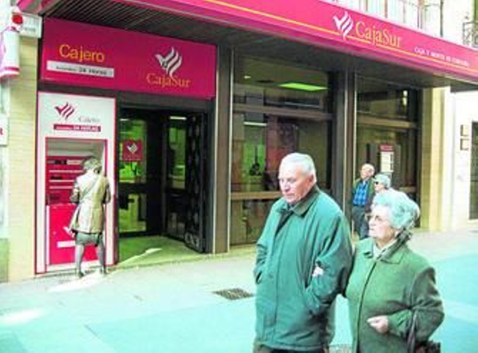 Varias personas pasan por una sucursal de Cajasur.