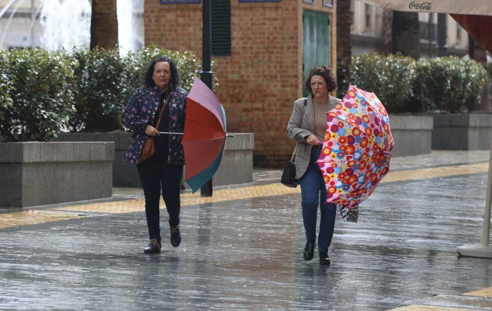 Dos señoras con sus paraguas este domingo en Huelva