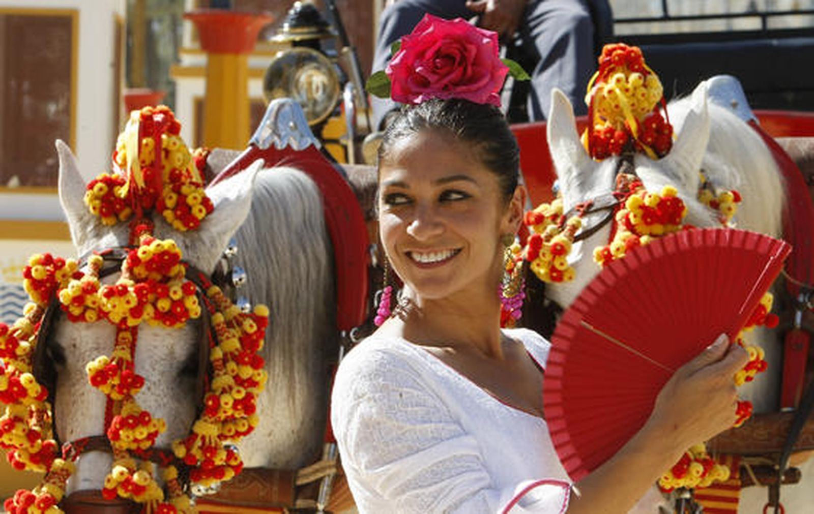 Colores vivos. Una bella flamenca sonríe mientras se abanica junto a un coche de caballos, ayer, en la Feria.

Foto: Pascual