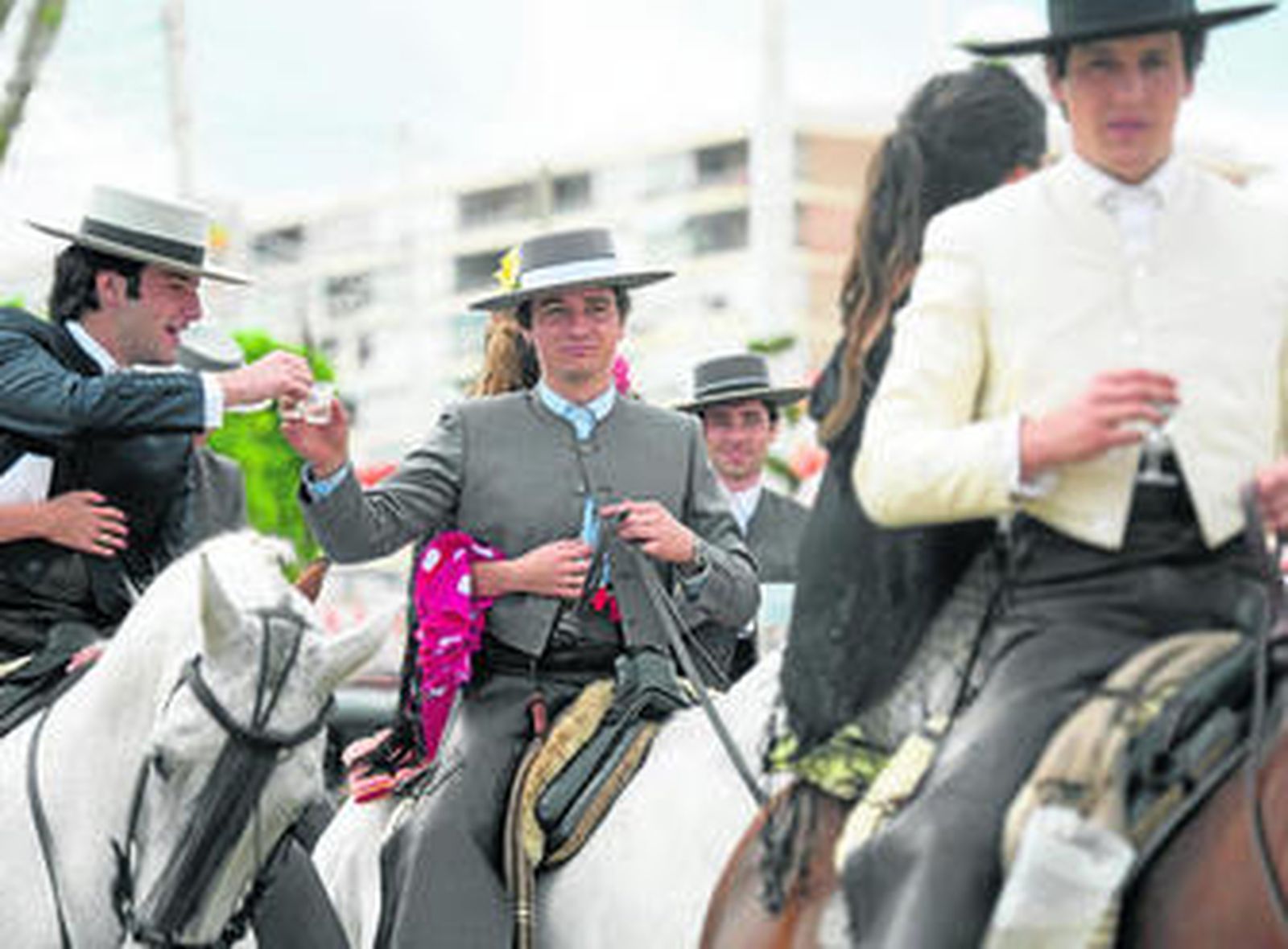 Dos jinetes brindan en el paseo de caballos durante el penúltimo día de Feria.