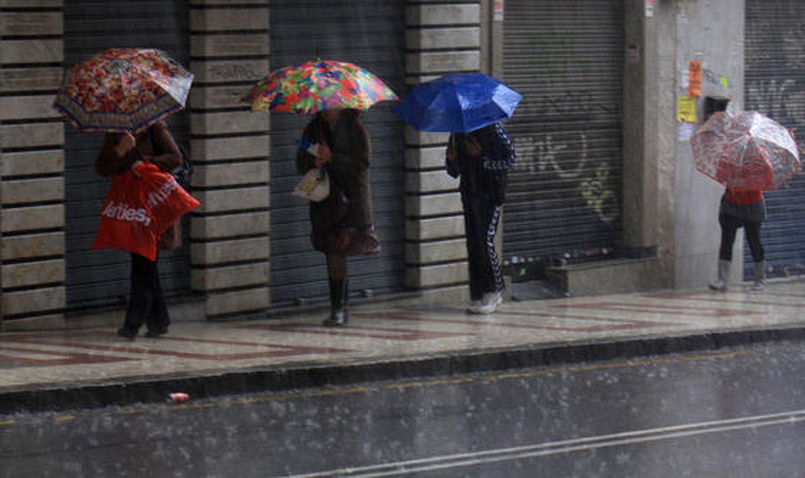 Los viandantes se protegen de la lluvia. / Migue Fernández