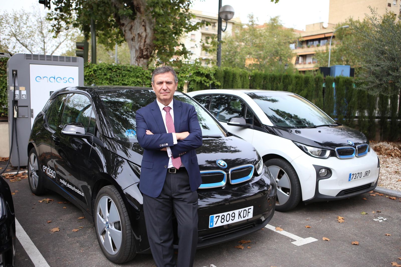 Francisco Arteana, en el aparcamiento de la sede de Endesa en Sevilla, apoyado en vehículos eléctricos repostando en un cargador superrápido.