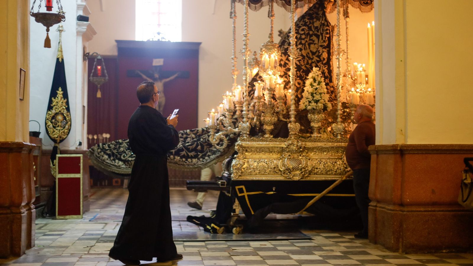 Un sacerdote realiza una foto al paso de palio de la Virgen de la Soledad en San Francisco.