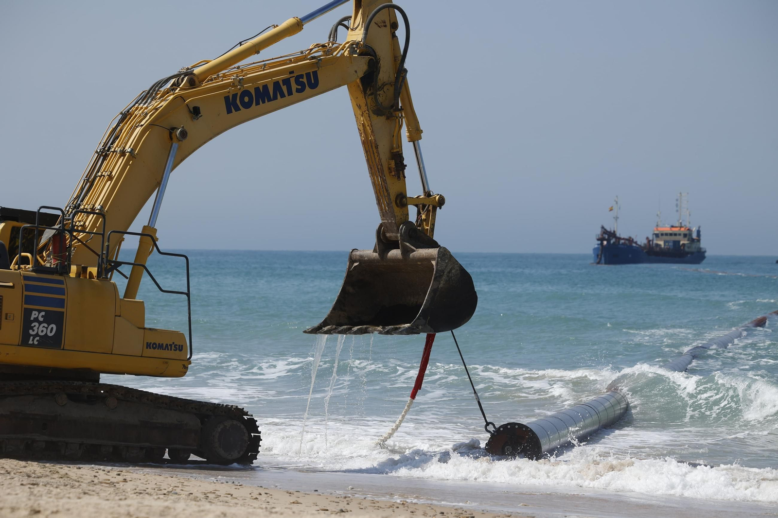 Tendiendo las tuberías que se utilizarán en la reposición de arena en la playa de Camposoto, este viernes